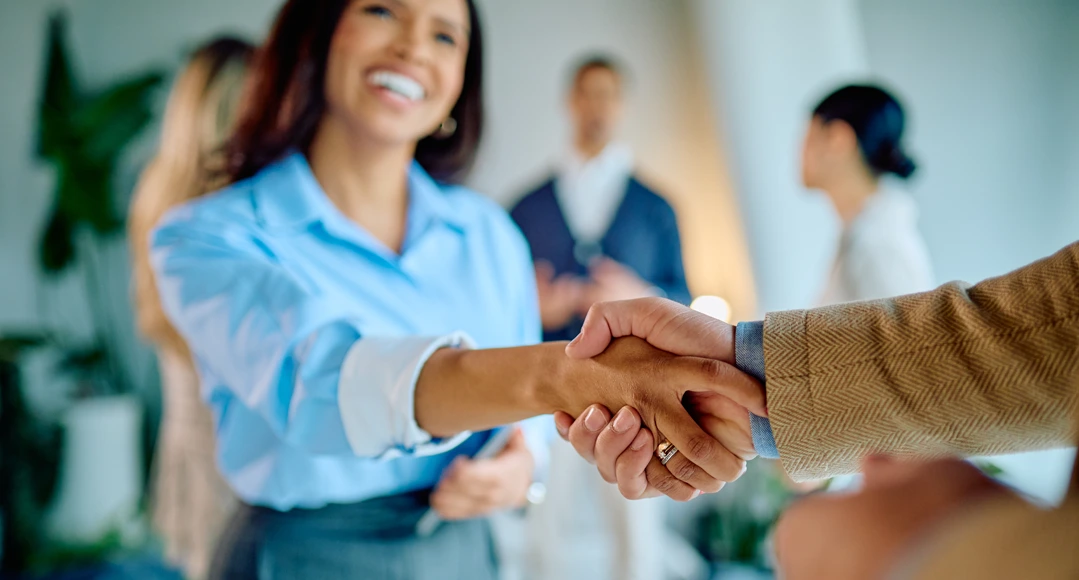A smiling woman shaking hands with a lender.