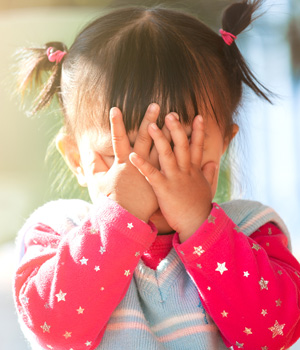 Cute little girl covering her face.