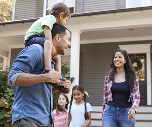 Smiling family outside their home.