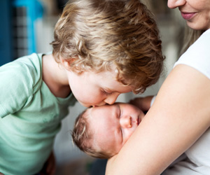 Older brother kissing his baby sibling