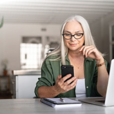 woman with a laptop and notebook is looking at her cell phone