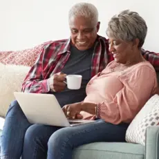 Smiling senior couple reviewing their finances on a laptop