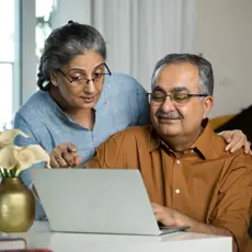 Smiling senior couple reviewing their finances on a laptop