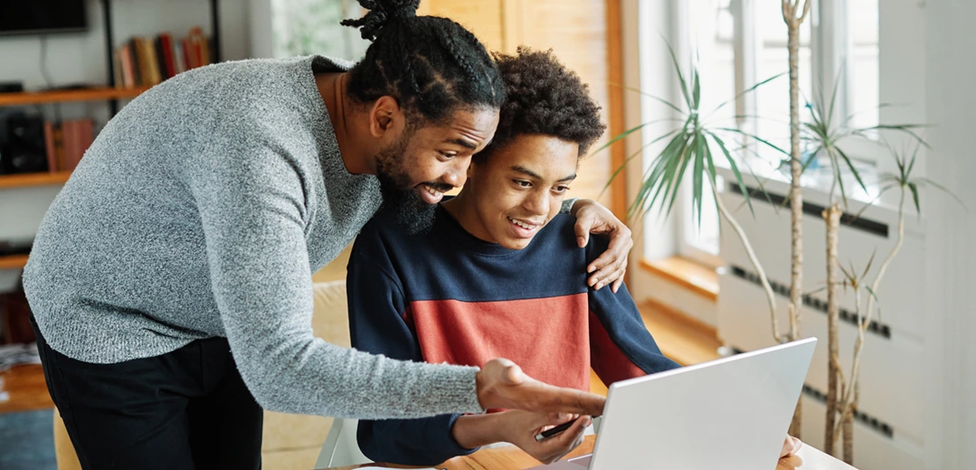 A father teaching his son about finances using a laptop