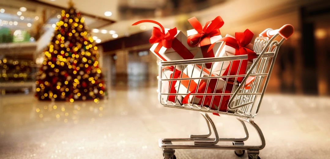 Shopping cart full of wrapped presents with a Christmas tree in the background